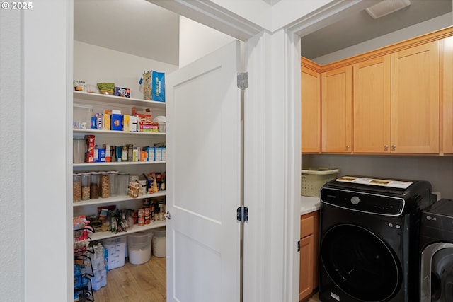 storage area with visible vents and washer and clothes dryer