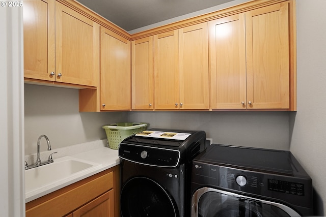 laundry room featuring cabinet space, separate washer and dryer, and a sink