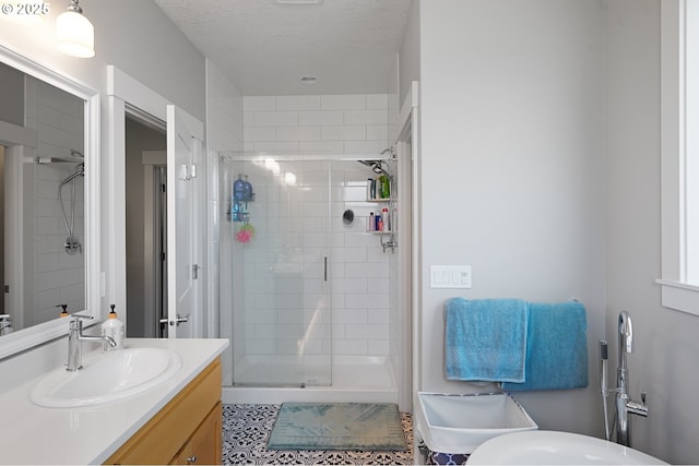 full bathroom with a shower stall, a textured ceiling, and vanity