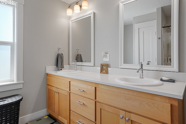 full bath featuring double vanity, a sink, and baseboards