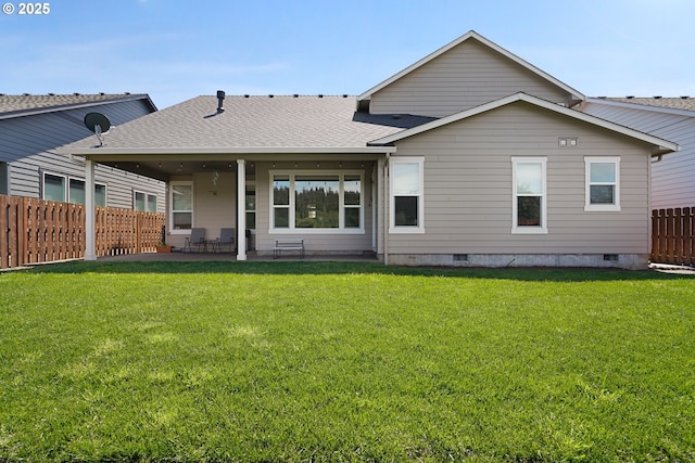 rear view of property with roof with shingles, a lawn, a patio area, and fence