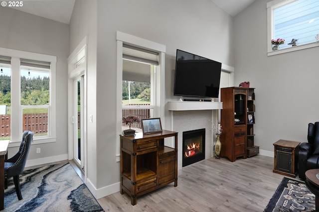 office area with a glass covered fireplace, plenty of natural light, wood finished floors, and baseboards