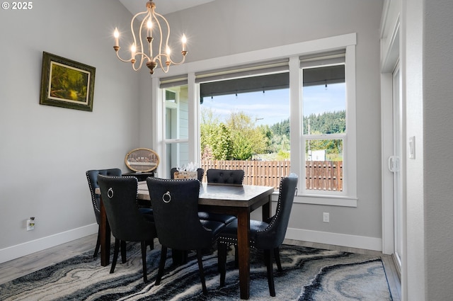 dining space with baseboards, wood finished floors, and a notable chandelier