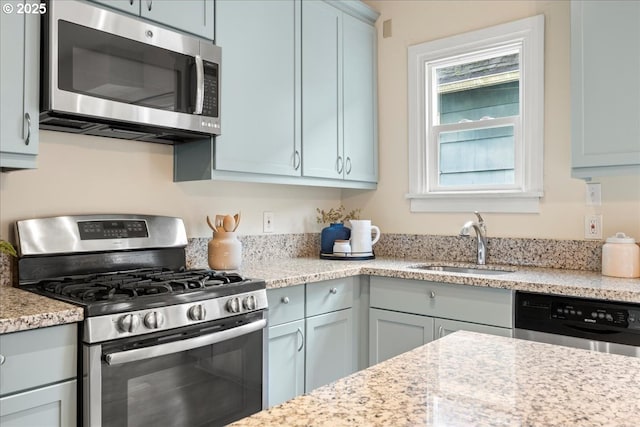 kitchen featuring light stone counters, sink, and stainless steel appliances