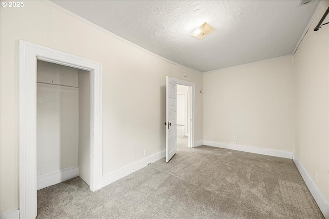 unfurnished bedroom featuring light carpet, a closet, a textured ceiling, and ornamental molding