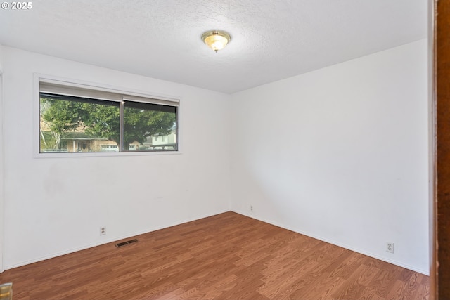 spare room featuring wood-type flooring and a textured ceiling