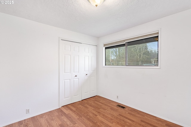 unfurnished bedroom featuring a closet, light hardwood / wood-style flooring, and a textured ceiling