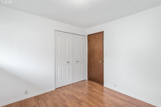 unfurnished bedroom with a closet, a textured ceiling, and light hardwood / wood-style flooring