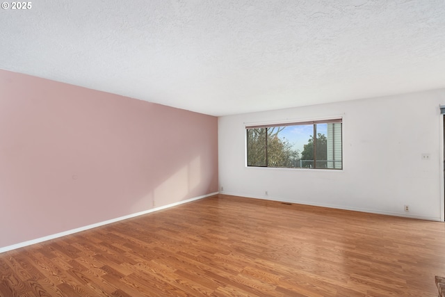 spare room featuring light hardwood / wood-style flooring and a textured ceiling