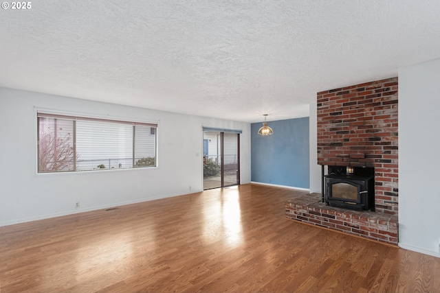 unfurnished living room with a wood stove, hardwood / wood-style floors, and a textured ceiling