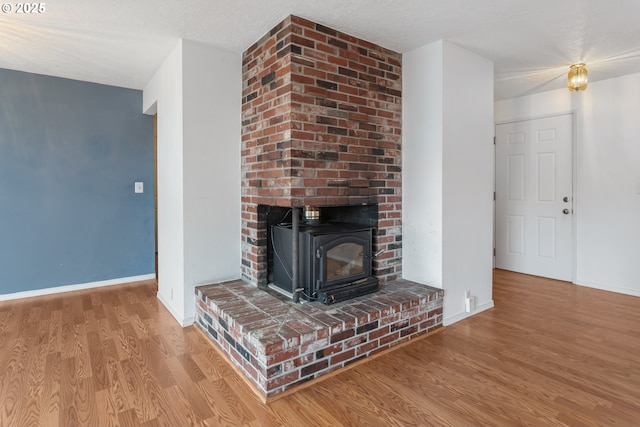 unfurnished living room with a wood stove, a textured ceiling, and light wood-type flooring