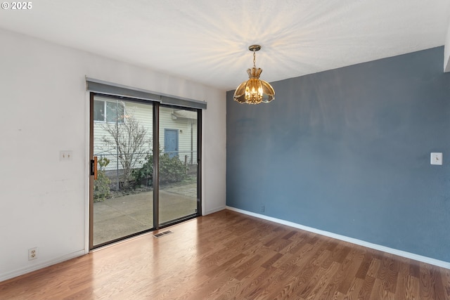 spare room featuring hardwood / wood-style floors and a notable chandelier