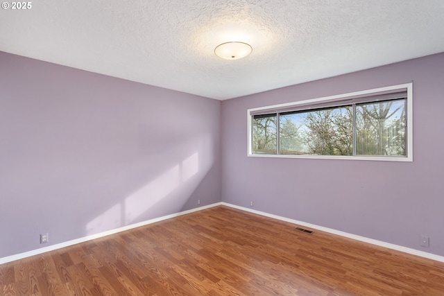 spare room featuring wood-type flooring and a textured ceiling