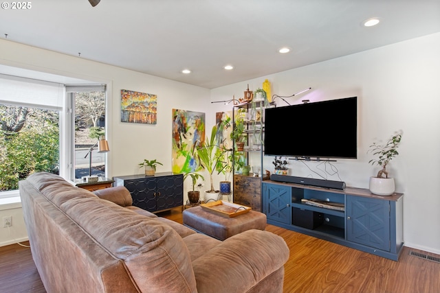 living area with recessed lighting, wood finished floors, visible vents, and baseboards