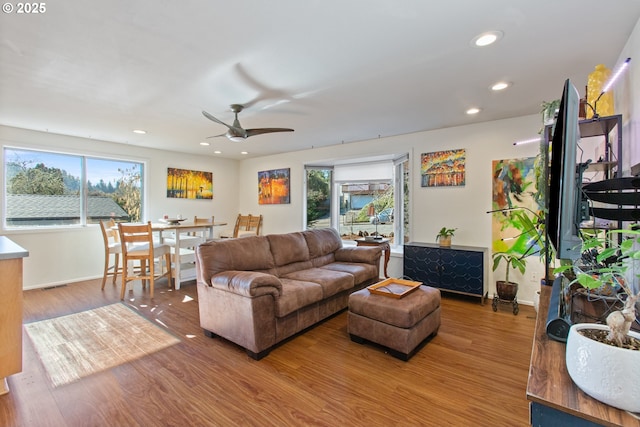 living room featuring a ceiling fan, visible vents, wood finished floors, baseboards, and recessed lighting