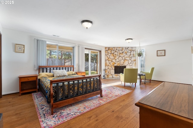 bedroom featuring visible vents, wood finished floors, and a fireplace