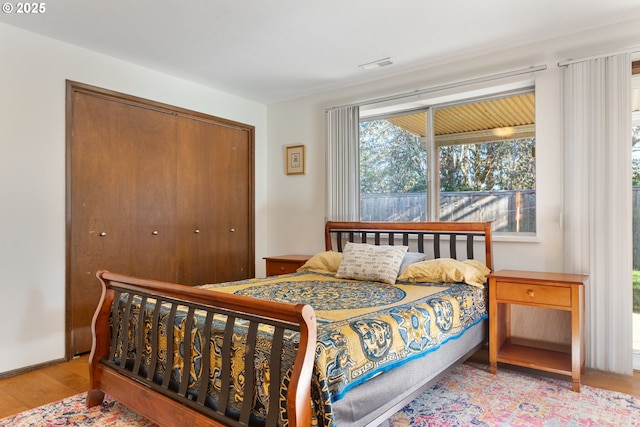 bedroom with wood finished floors, visible vents, and a closet