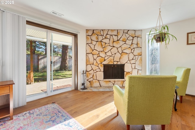 living area with wood finished floors, a fireplace, and visible vents