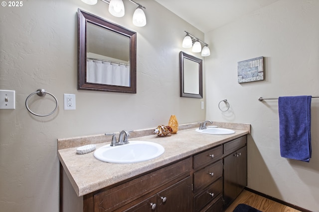 full bath with a sink, wood finished floors, and double vanity