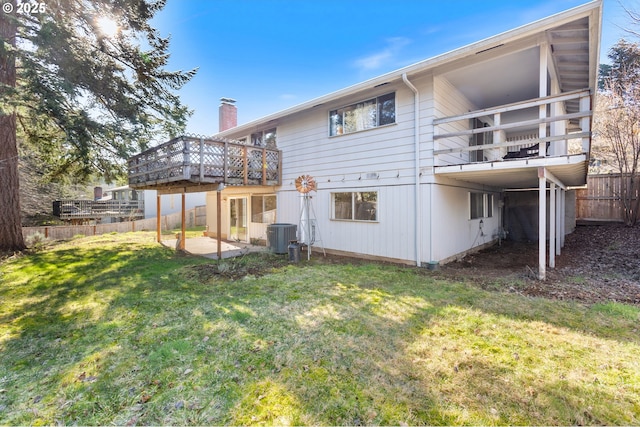 rear view of property featuring cooling unit, fence, a wooden deck, a chimney, and a lawn