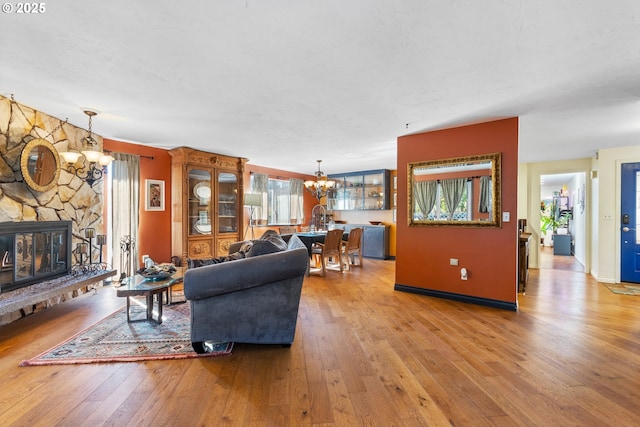 living area with hardwood / wood-style floors, a notable chandelier, a fireplace, and baseboards