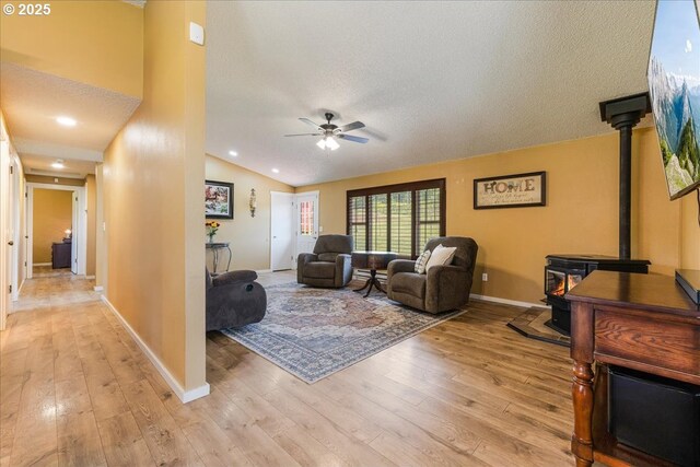 18203 S Windy City Rd, Mulino, OR 97042 - living room featuring a wood stove, light wood-style floors, a ceiling fan, baseboards, and a textured ceiling