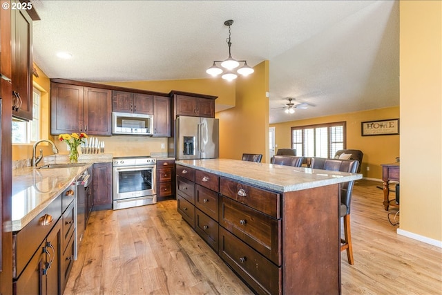 18203 S Windy City Rd, Mulino, OR 97042 - kitchen with appliances with stainless steel finishes, a sink, vaulted ceiling, a kitchen bar, and light wood-style floors