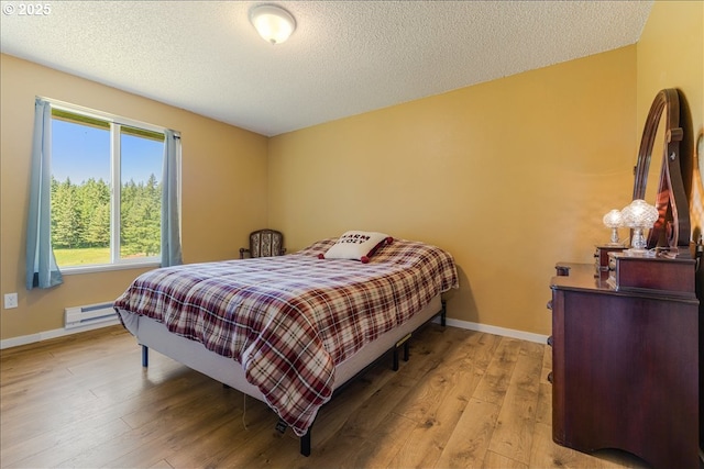 18203 S Windy City Rd, Mulino, OR 97042 - bedroom featuring light wood-type flooring, a baseboard heating unit, a textured ceiling, and baseboards