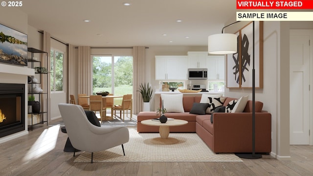 interior space featuring a glass covered fireplace, baseboards, light wood finished floors, and recessed lighting