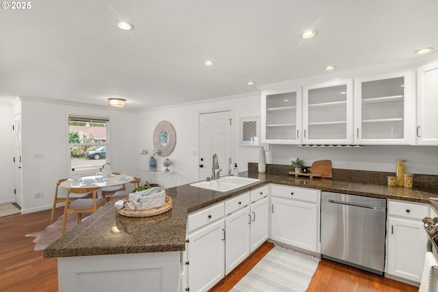 kitchen featuring a peninsula, stainless steel dishwasher, wood finished floors, white cabinetry, and a sink