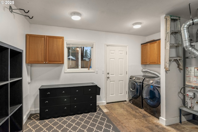 washroom featuring baseboards, cabinet space, water heater, and washing machine and clothes dryer