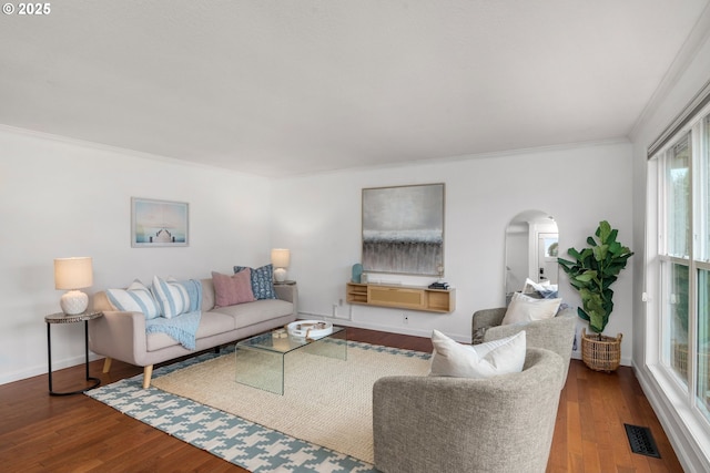 living room with visible vents, ornamental molding, wood finished floors, arched walkways, and baseboards