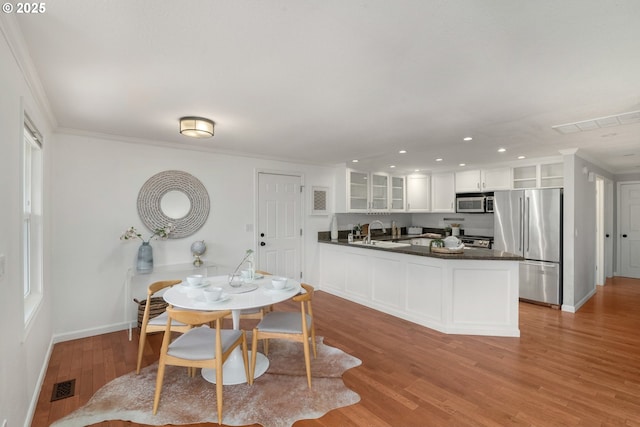 dining area featuring visible vents, light wood-style flooring, crown molding, and baseboards