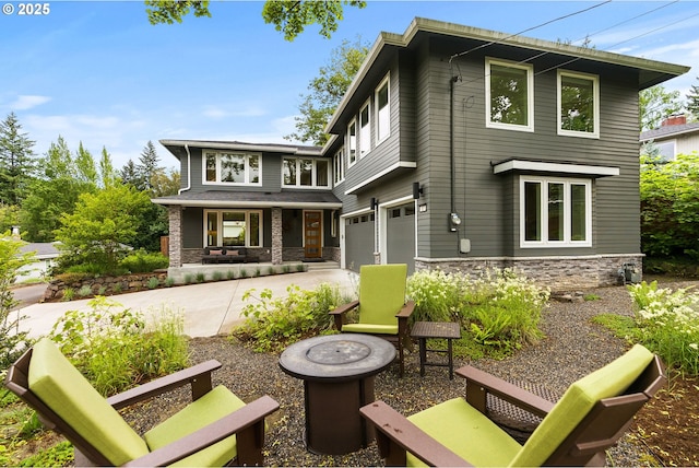 927 SW Maplecrest Ct, Portland, OR 97219 - rear view of house with stone siding, covered porch, concrete driveway, and an attached garage