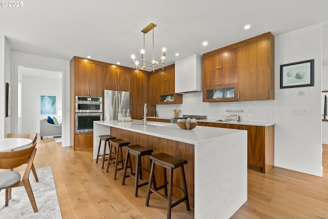 927 SW Maplecrest Ct, Portland, OR 97219 - kitchen with appliances with stainless steel finishes, brown cabinets, a sink, light wood-style floors, and recessed lighting
