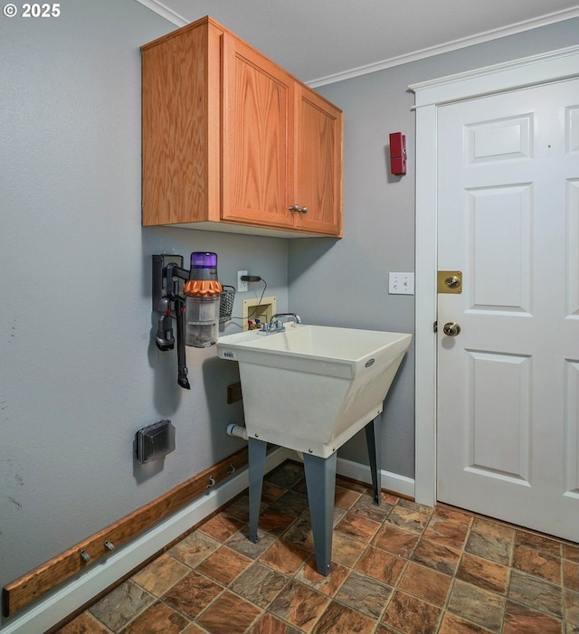 laundry room with stone finish flooring, washer hookup, baseboards, crown molding, and cabinet space