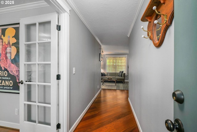 hallway with crown molding, wood finished floors, baseboards, and a textured ceiling