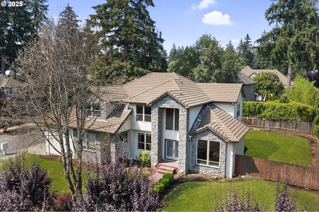 view of front facade with a front yard, stone siding, and fence