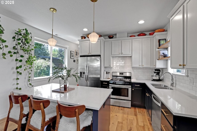 9115 N Richmond Ave, Portland, OR 97203 - kitchen featuring stainless steel appliances, a sink, open shelves, light wood-style flooring, and recessed lighting