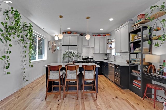 9115 N Richmond Ave, Portland, OR 97203 - kitchen with appliances with stainless steel finishes, a sink, light wood finished floors, a breakfast bar, and backsplash