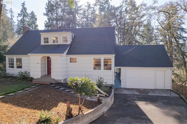 view of front of property featuring driveway, a shingled roof, a chimney, and an attached garage