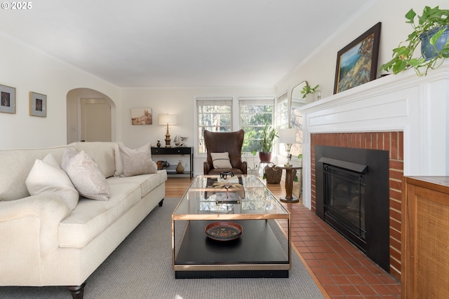 tiled living room featuring a fireplace, arched walkways, and crown molding