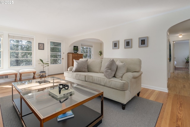 living room featuring light wood-type flooring, arched walkways, and baseboards