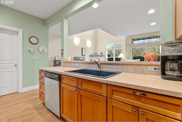 kitchen with sink, stainless steel dishwasher, and light wood-type flooring