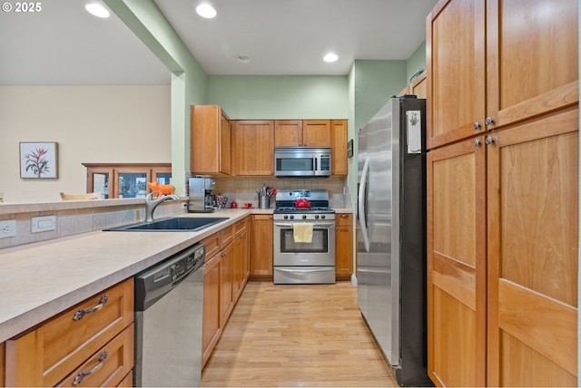 kitchen featuring tasteful backsplash, appliances with stainless steel finishes, sink, and light hardwood / wood-style flooring