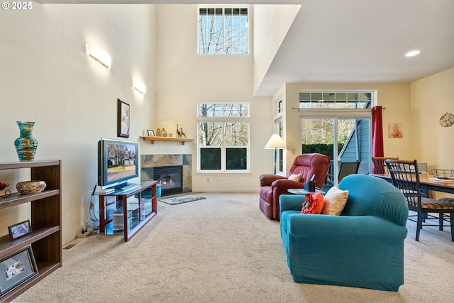 living room with a towering ceiling, carpet floors, and a tile fireplace