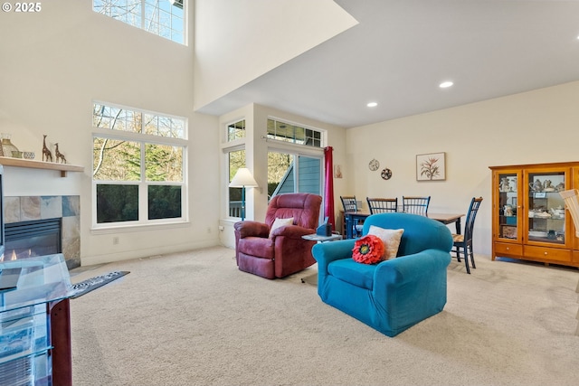 carpeted living room with a tile fireplace and a towering ceiling