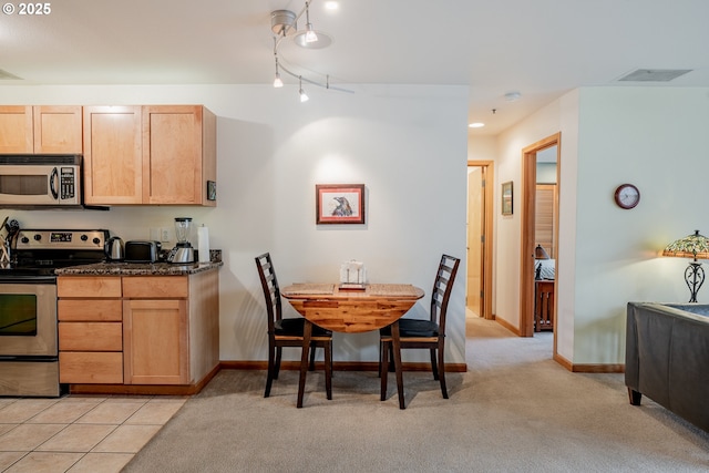 606 NW Naito Pkwy Unit A14, Portland, OR 97209 - kitchen featuring light brown cabinetry, track lighting, light carpet, stainless steel appliances, and baseboards