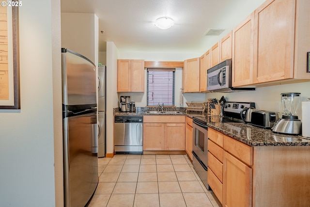 606 NW Naito Pkwy Unit A14, Portland, OR 97209 - kitchen with light brown cabinetry, a sink, dark stone countertops, appliances with stainless steel finishes, and light tile patterned floors