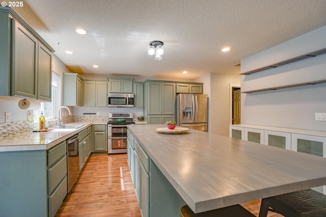 2301 NW 15th St, Battle Ground, WA 98604 - kitchen with stainless steel appliances, green cabinetry, light wood-type flooring, and a sink